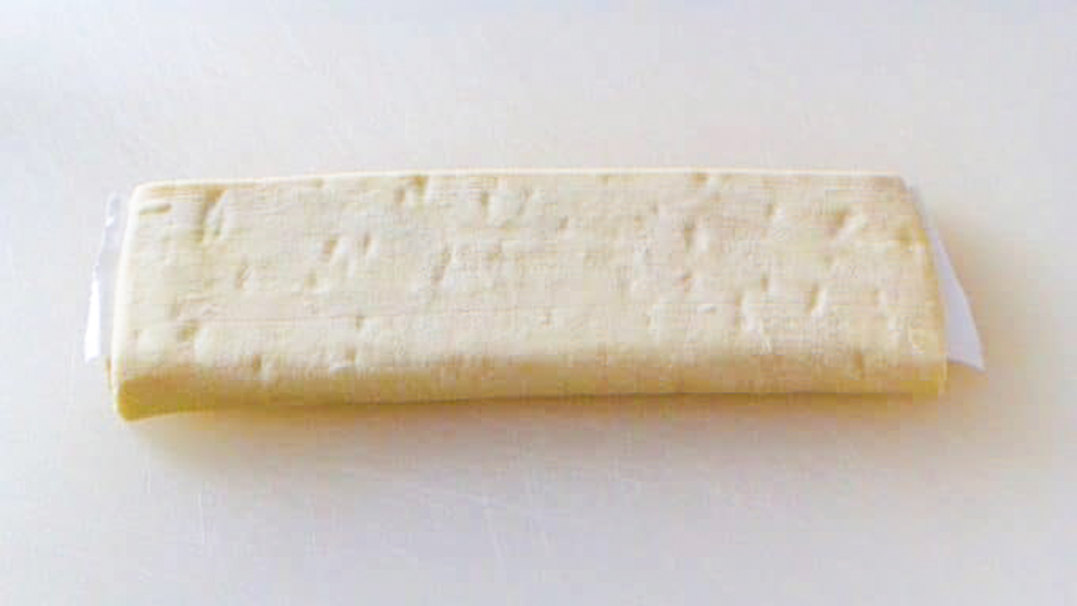 Folded sheet of puff pastry on a cutting board ready to unfold, roll with a rolling pin and to use in a recipe.
