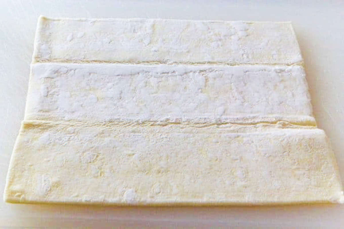 Puff pastry sheets unfolded on a cutting board ready to use in a recipe.