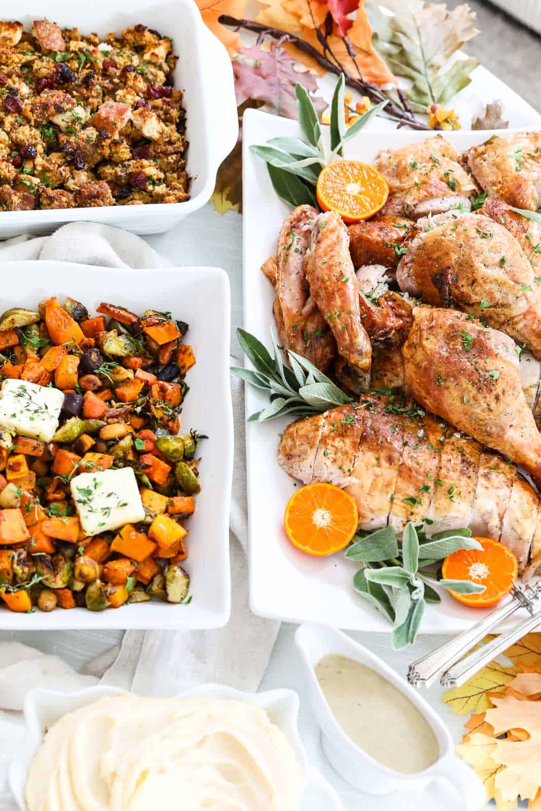 A Thanksgiving table of dishes including sliced roast turkey