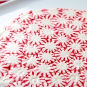 A peppermint candy plate made from peppermints with a pile of fresh baked colorful Christmas cookies.