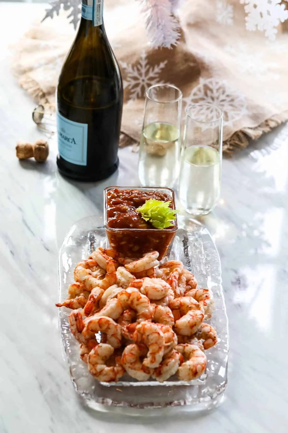 Cooked shrimp on a glass platter with cocktail to served at a Christmas party with champagne.