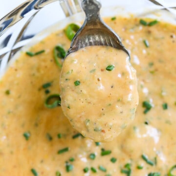 Vintage silver spoon filled with remoulade sauce garnished with snips of green chives.