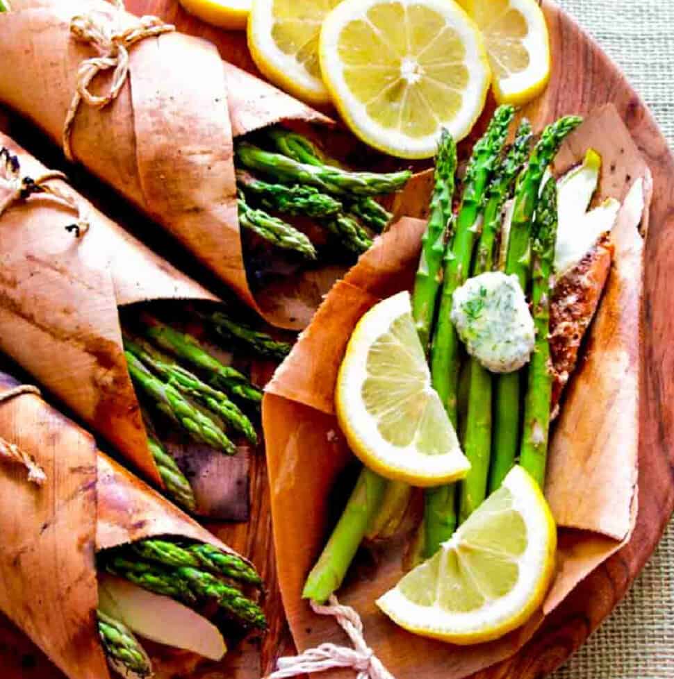 Cedar wrapped grilled salmon with asparagus and lemon slices on a platter.
