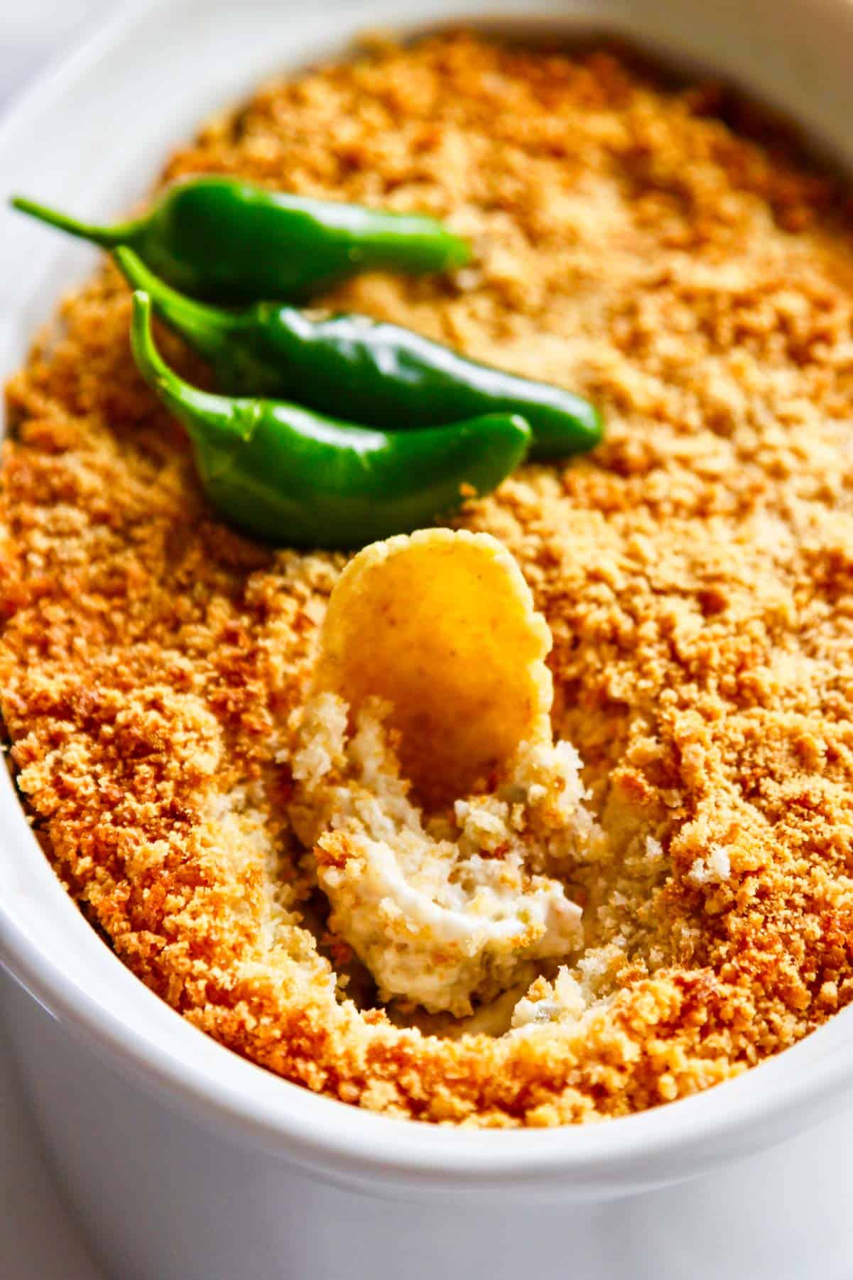 A large corn chip stuck into jalapeno popper dip.