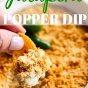 A person scooping our a large corn chip of jalapeno popper dip.