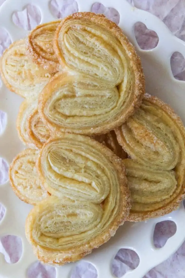 A white heart shaped dish filled with fresh baked palmiers.