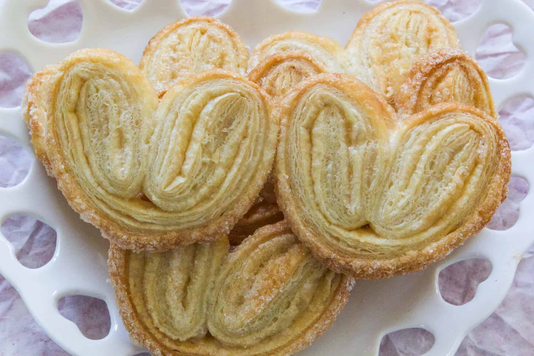 A white plate full of palmiers ready to eat as dessert.