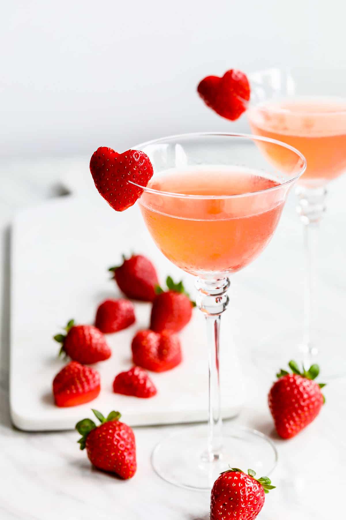 Pink strawberry cocktails with whole berries and heart shaped garnish.