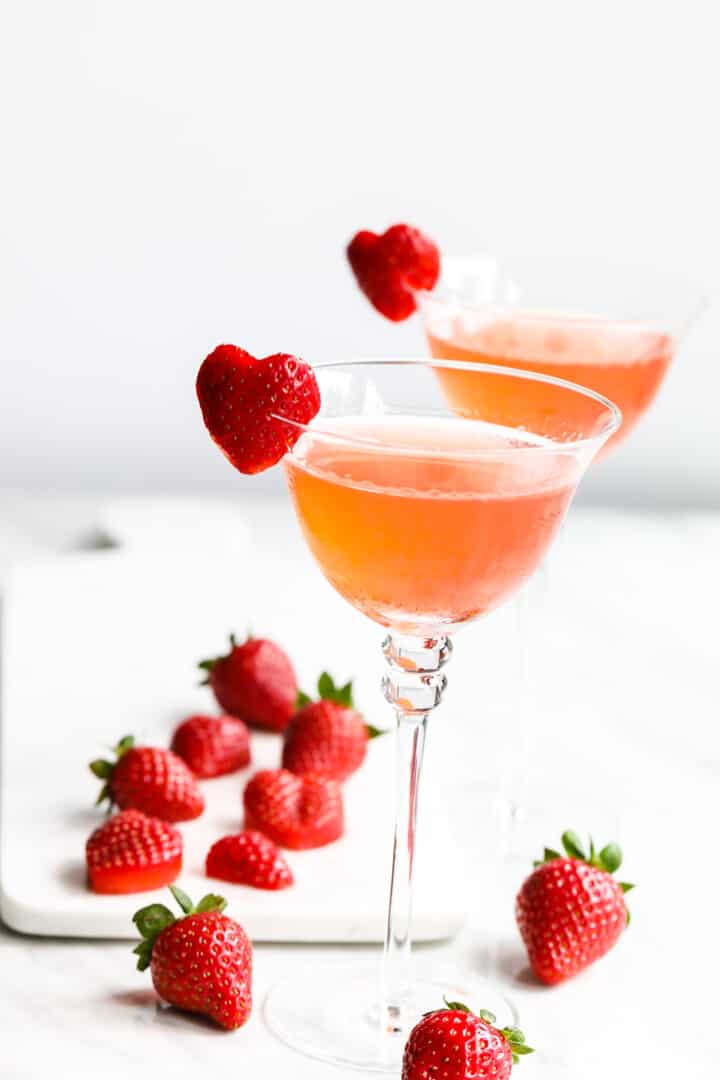 Two glasses of strawberry cocktails with heart shaped strawberry garnish.