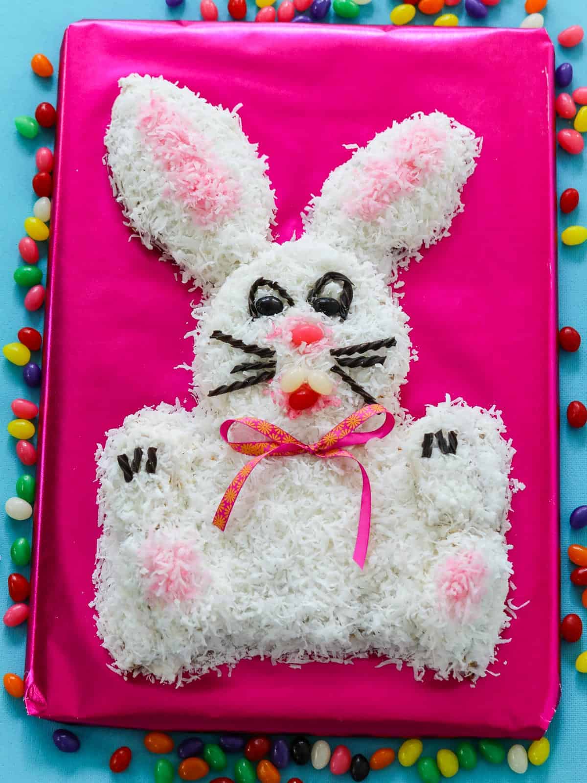 One of the best Easter Dinner Ideas, an adorable bunny cake on a hot pink table surrounded with jelly beans.