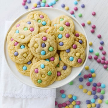 A white plate filled with freshly baked cake mix cookies with pastel m&m candies.
