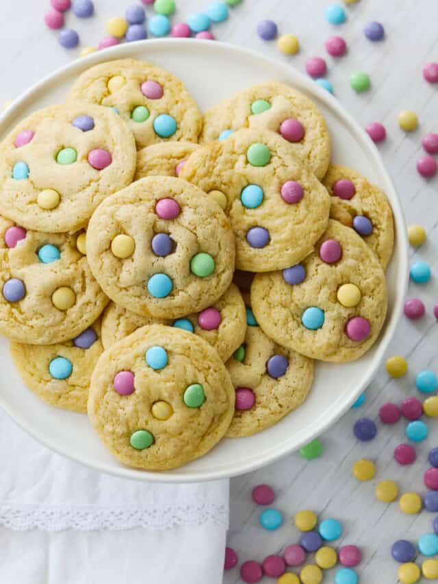 A white plate filled with freshly baked cake mix cookies with pastel m&m candies.