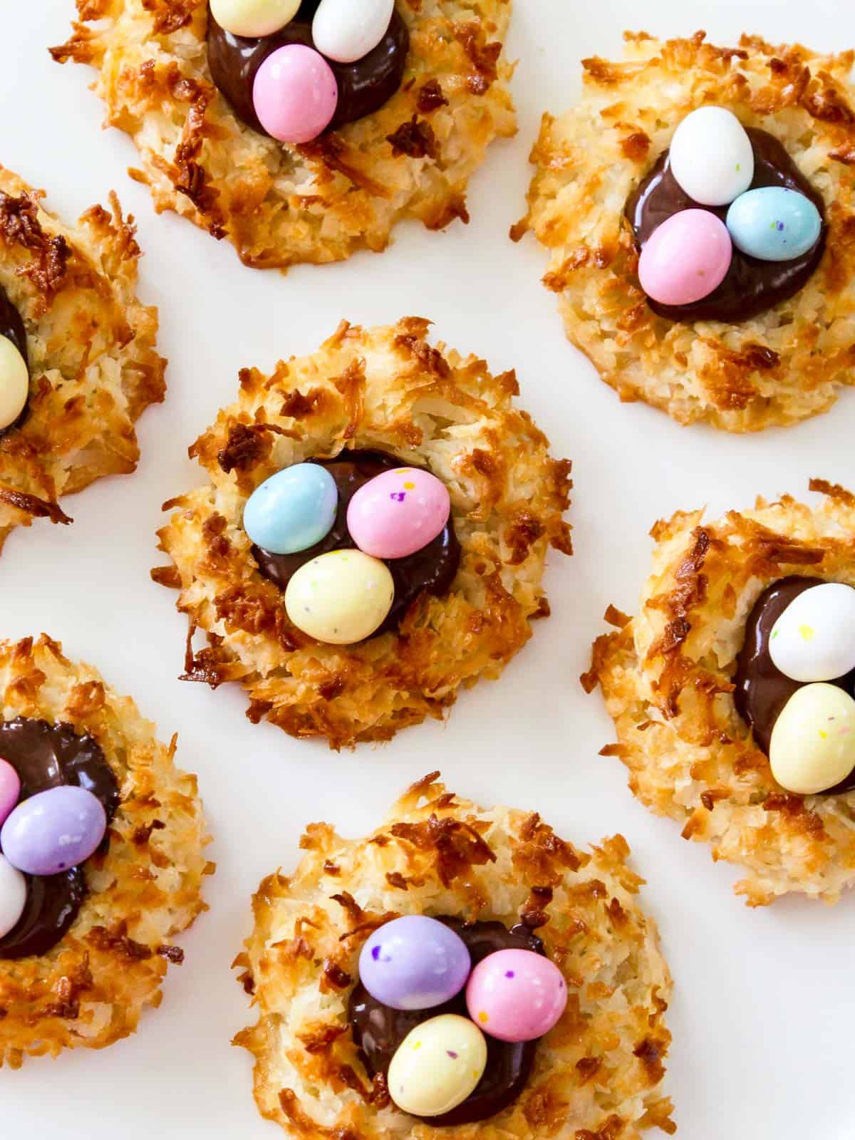 A white plate filled with Easter coconut macaroons decorate with chocolate eggs.