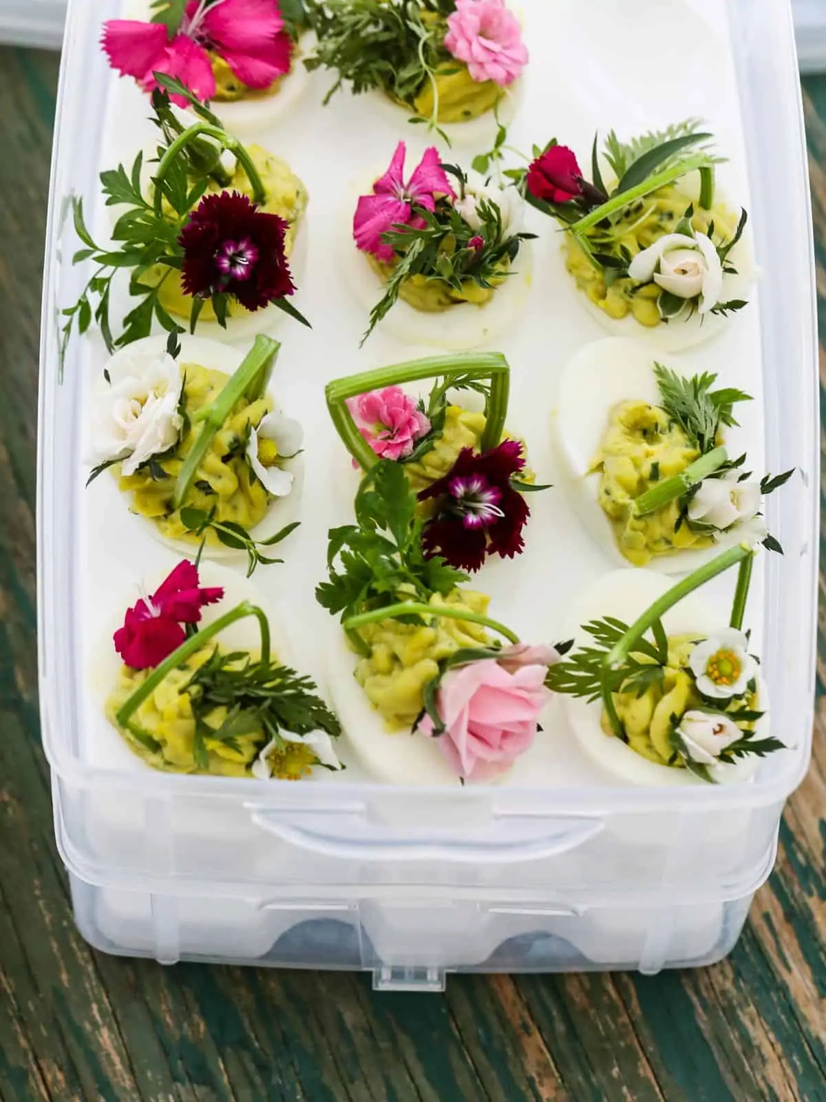 A plastic box designed to carry deviled eggs filled with Easter deviled eggs to take to a party.