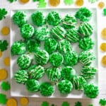 A square white plate with green oreos decorated with shamrock sprinkles.
