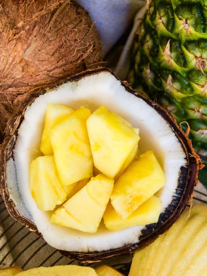 A coconut cracked open with fresh pineapple pieces inside.
