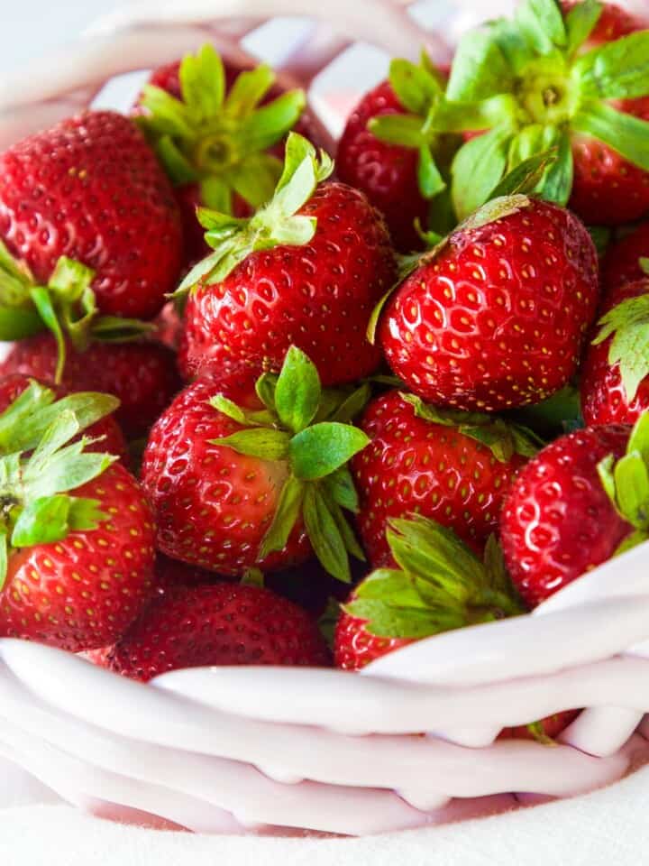 Fresh bright red real strawberries in a pink ceramic basket ready to bake into a strawberry cake.