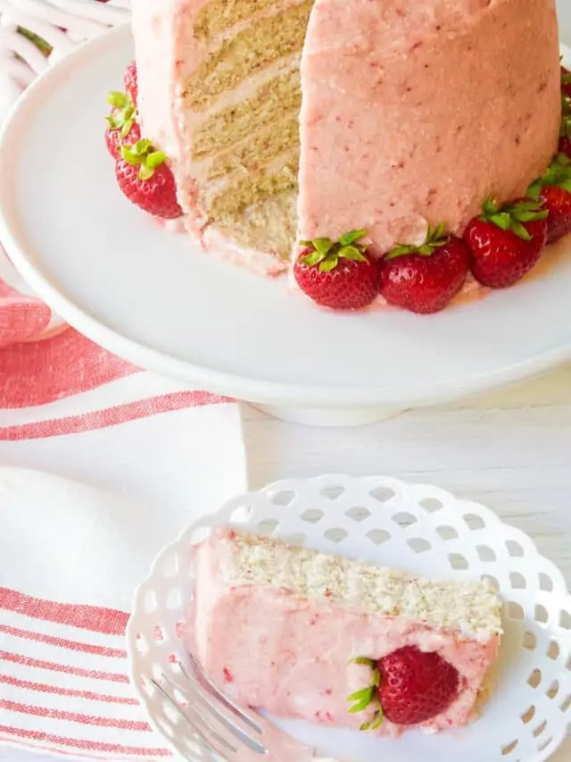 A freshly baked and decorated strawberry cake with real strawberries as decorations.