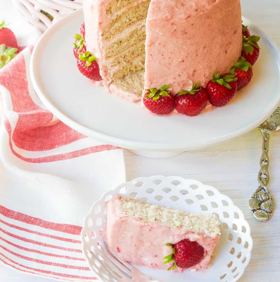 A freshly baked and decorated strawberry cake with real strawberries as decorations.