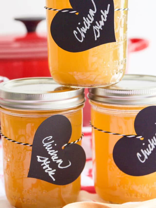 3 small Mason jars filled with chicken stock and black heart shaped labels.