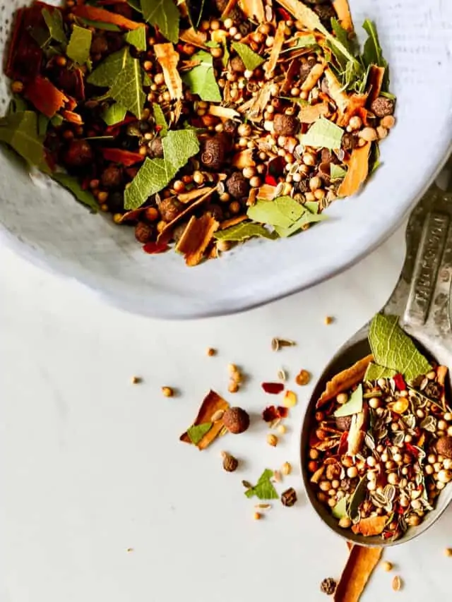 A recipe to make homemade pickling spice in a white bowl.