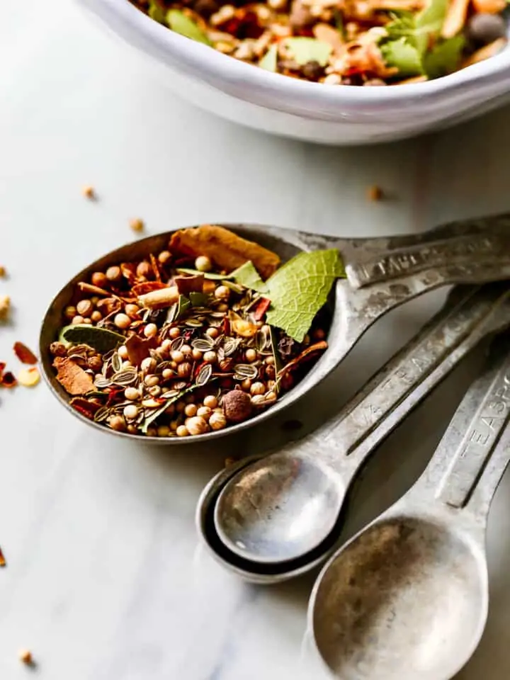 A close up view of pickling spice in a vintage tablespoon measuring spoon.