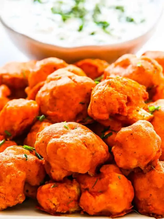 Baked Buffalo Cauliflower on a plate with ranch dip sprinkled with fresh herbs.
