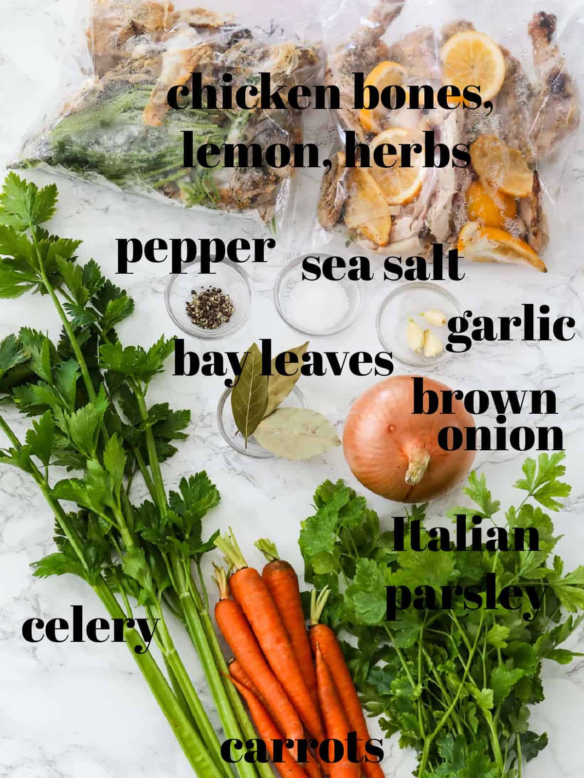 A table filled with ingredients to make a chicken stock recipe all labeled.