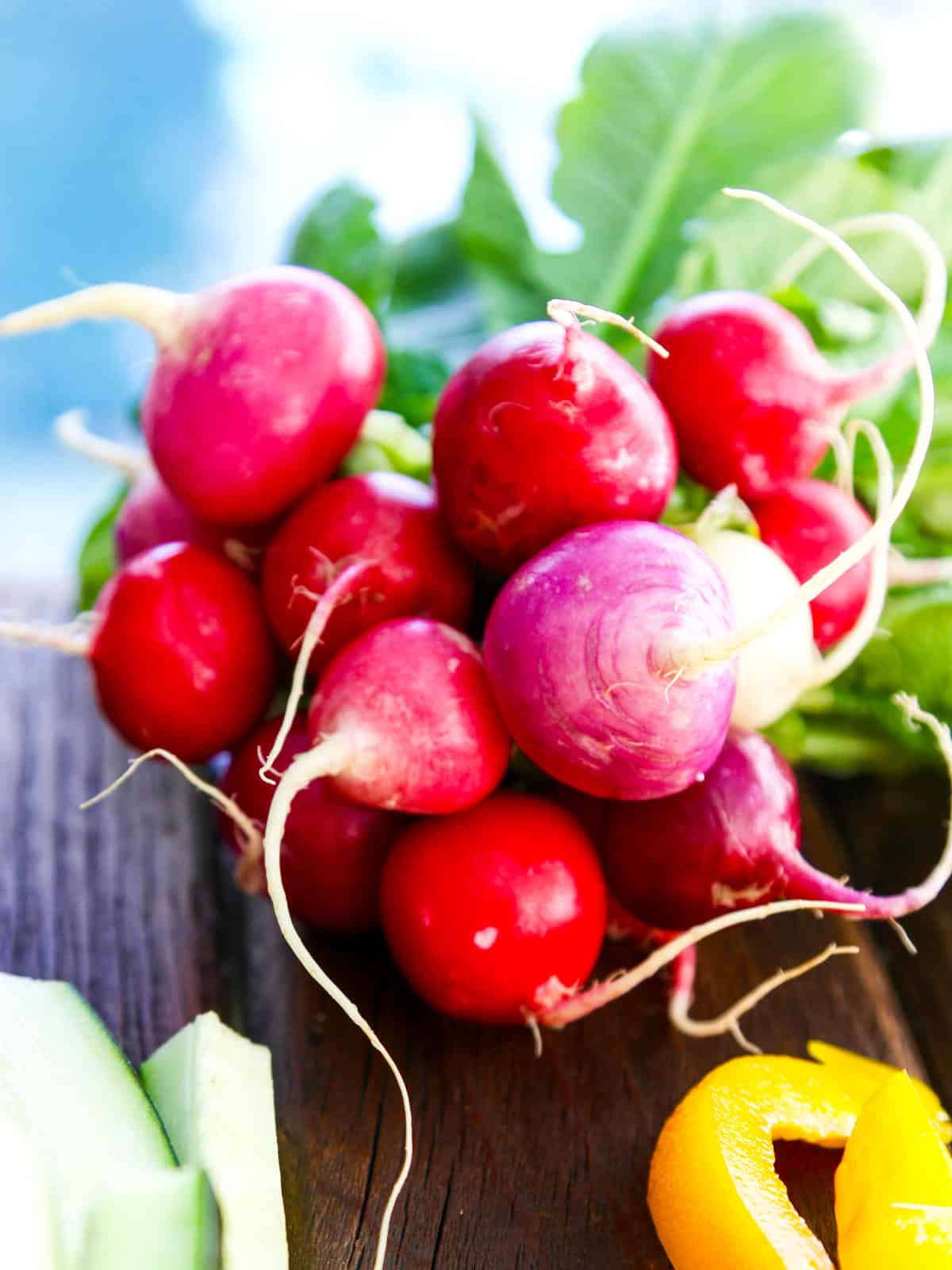 A bunch of bright red colorful radishes tied in a bundle on a board.