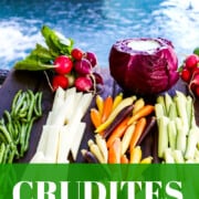 Vegetables on a cutting board with dip served in a purple cabbage out by a pool.