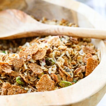 A wooden bowl filled with granola and a wooden spoon.