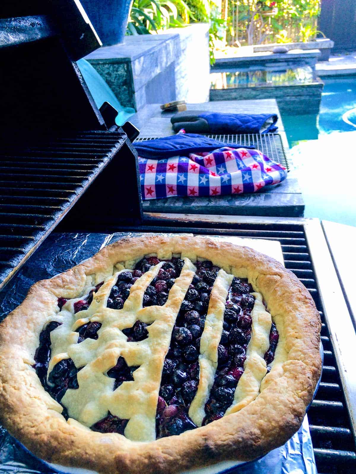 A blueberry pie with a flag crust baked on a grill.