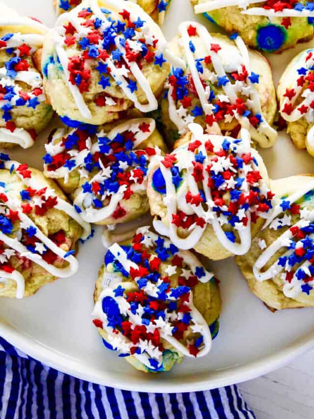 A white plate filled with July 4th red white and blue cookies with icing and star sprinkles.