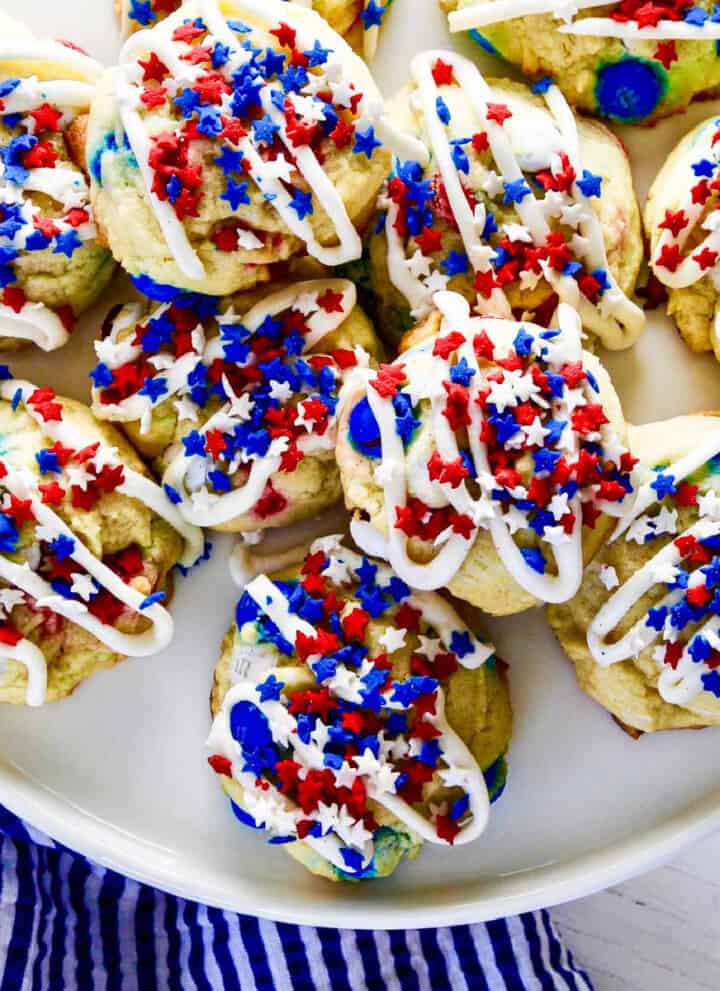 A white plate filled with July 4th red white and blue cookies with icing and star sprinkles.