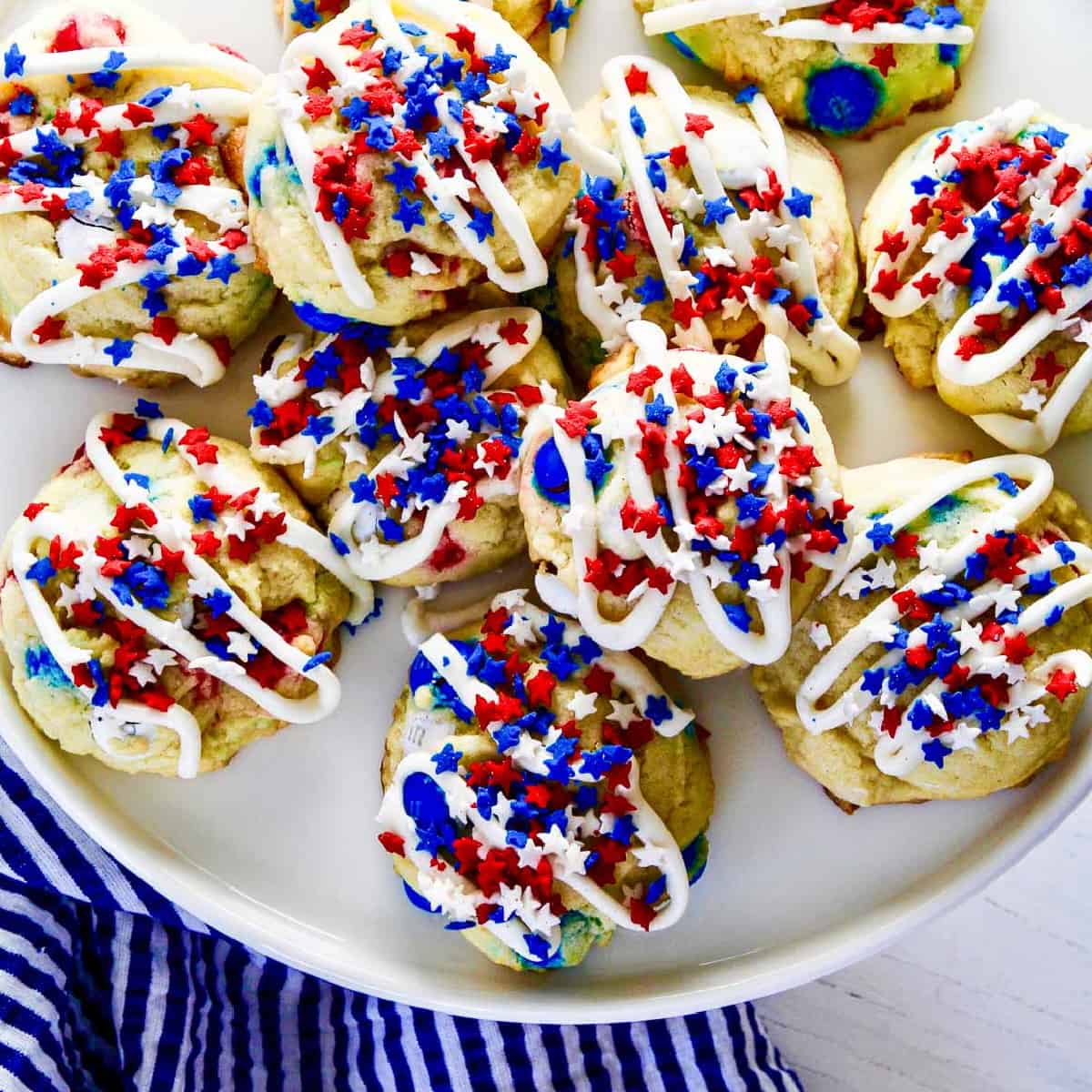A white plate filled with July 4th red white and blue cookies with icing and star sprinkles.
