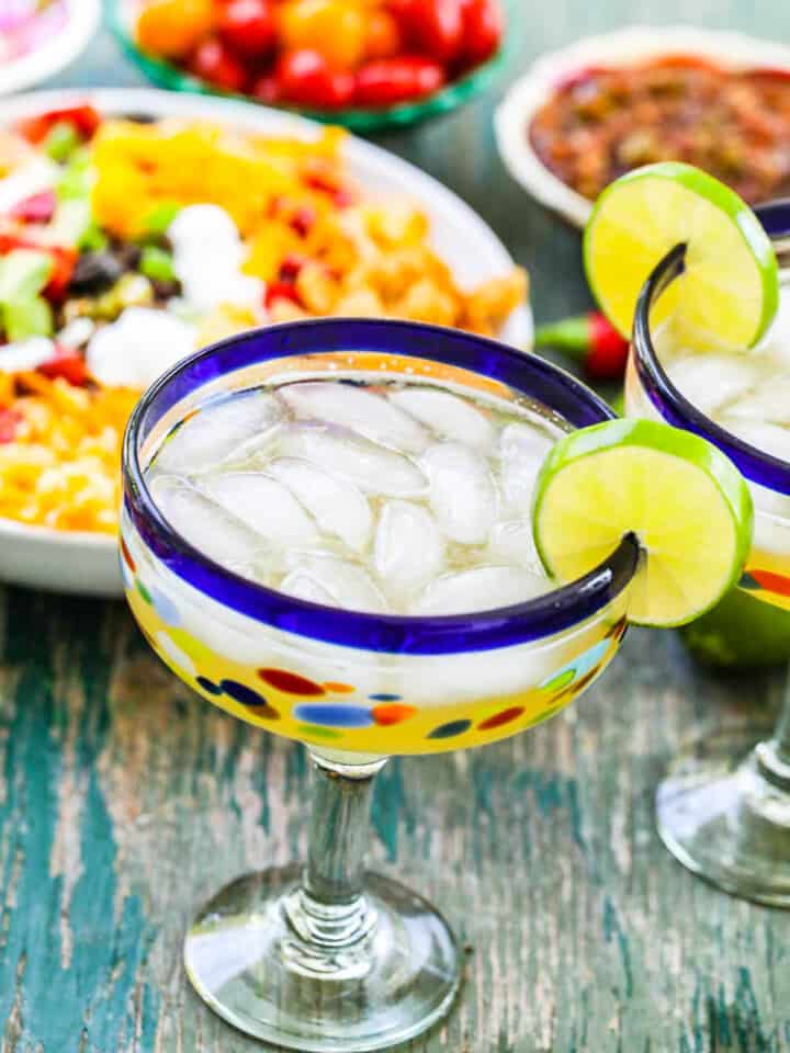 A blue rimmed Mexican glass filled with a margarita garnished with a lime.