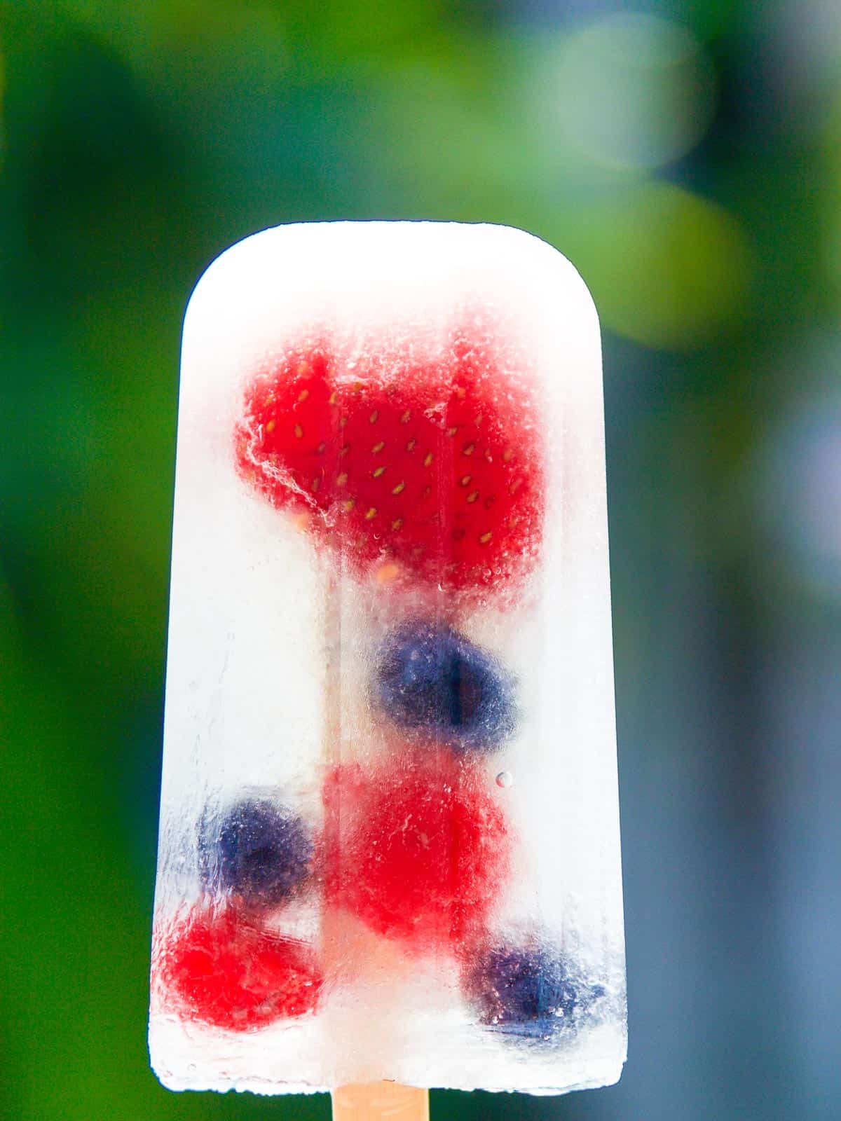 A single coconut water popsicle with strawberries, blueberries, and raspberries.