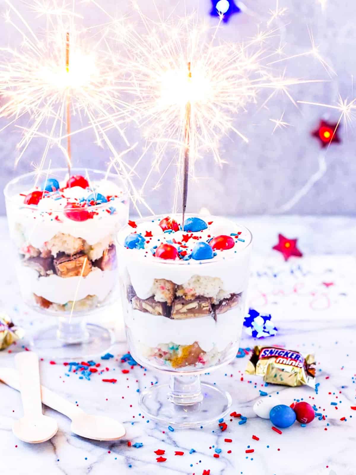 Small glass trifles filled with candy, whip cream, and July 4th sprinkles.