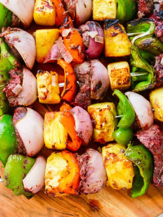 A wooden platter filled with Shish Kabob grilled skewers.