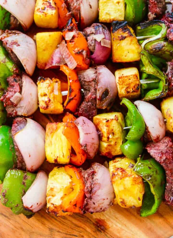 A wooden platter filled with Shish Kabob grilled skewers.