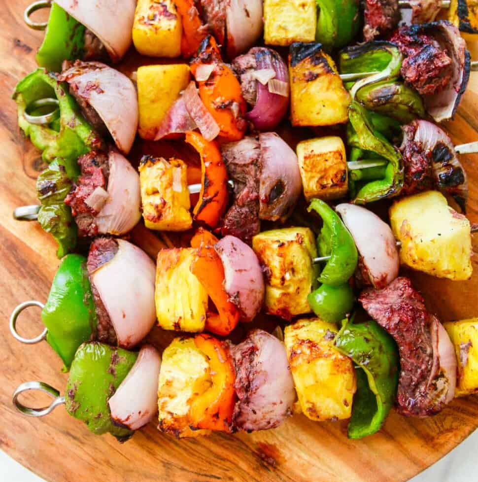 A wooden platter filled with Shish Kabob grilled skewers.