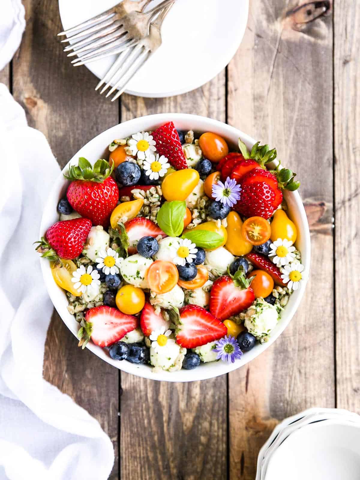 A strawberry, tomato summer salad garnished with little daisies.