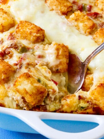 A vintage silver serving spoon taking out a piece of tater tot casserole just baked.