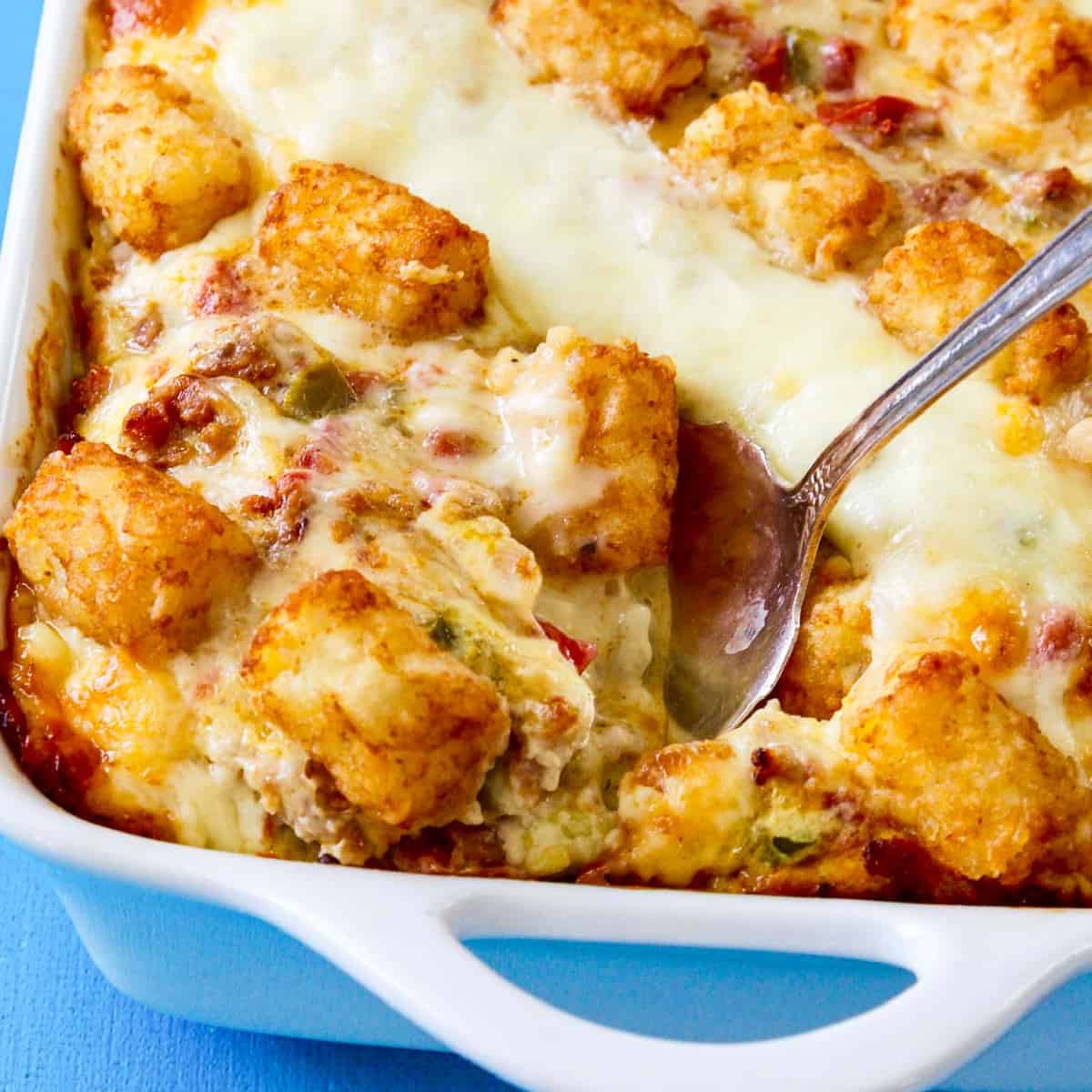 A vintage silver serving spoon taking out a piece of tater tot casserole just baked.