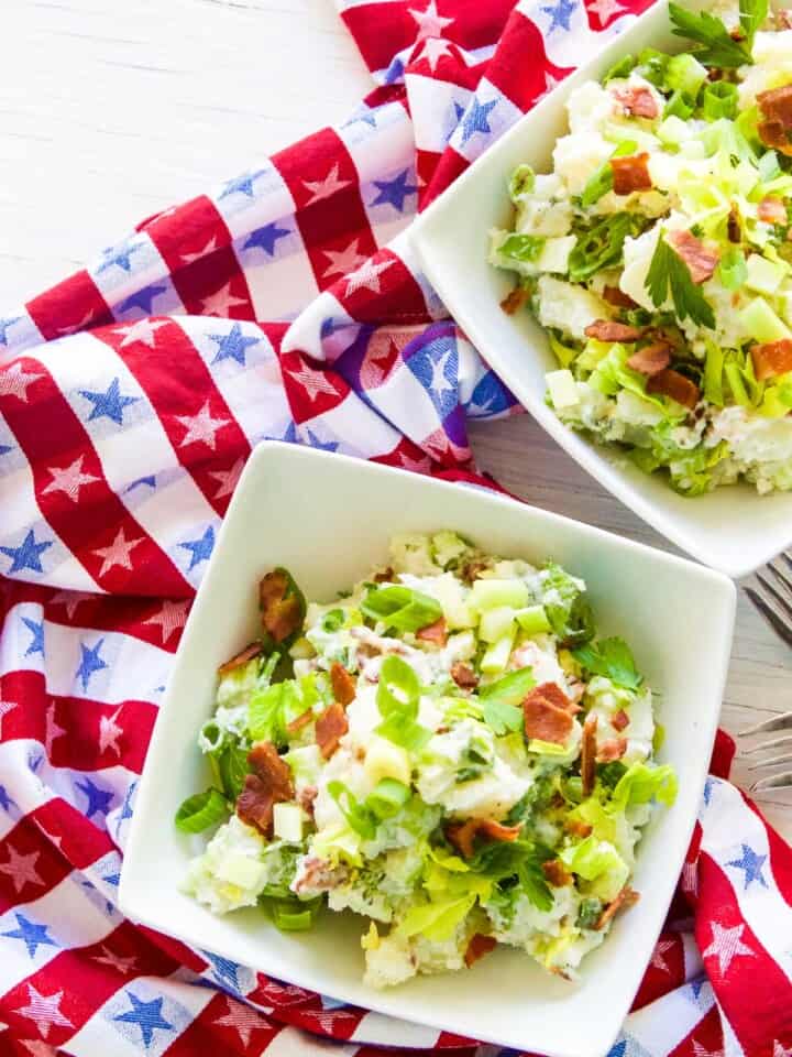 Two bowls of potato salad for July 4th on a red white and blue star towel and silver forks.