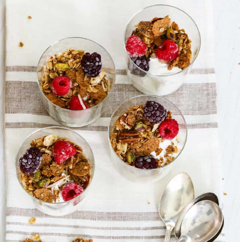 Four small yogurt parfaits made with yogurt, granola and berries.