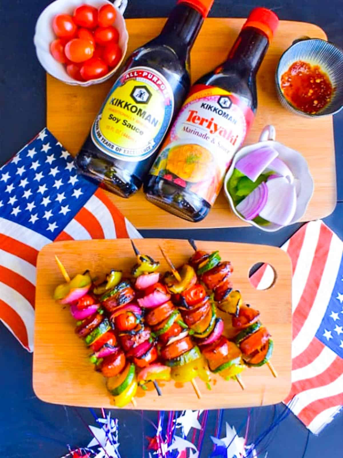 A cutting board with bright colored kebabs with vegetables and sausages at a July 4th party.