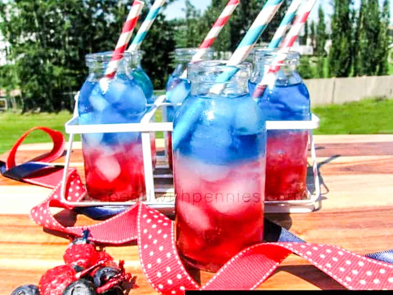 Four glasses of red white and blue drinks with straws at a July 4th party.