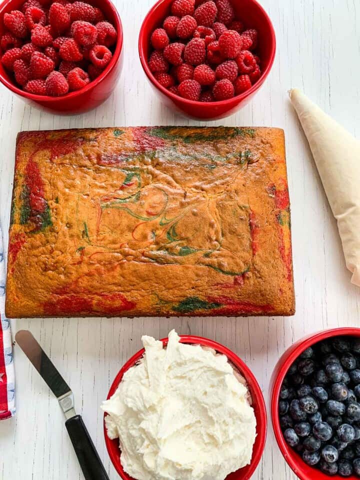 A sheet can, frosting, and berries to decorate a cake.