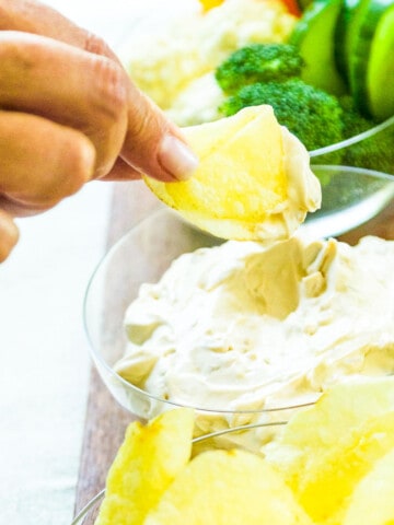 A lady dipping a potato chip into onion dip.